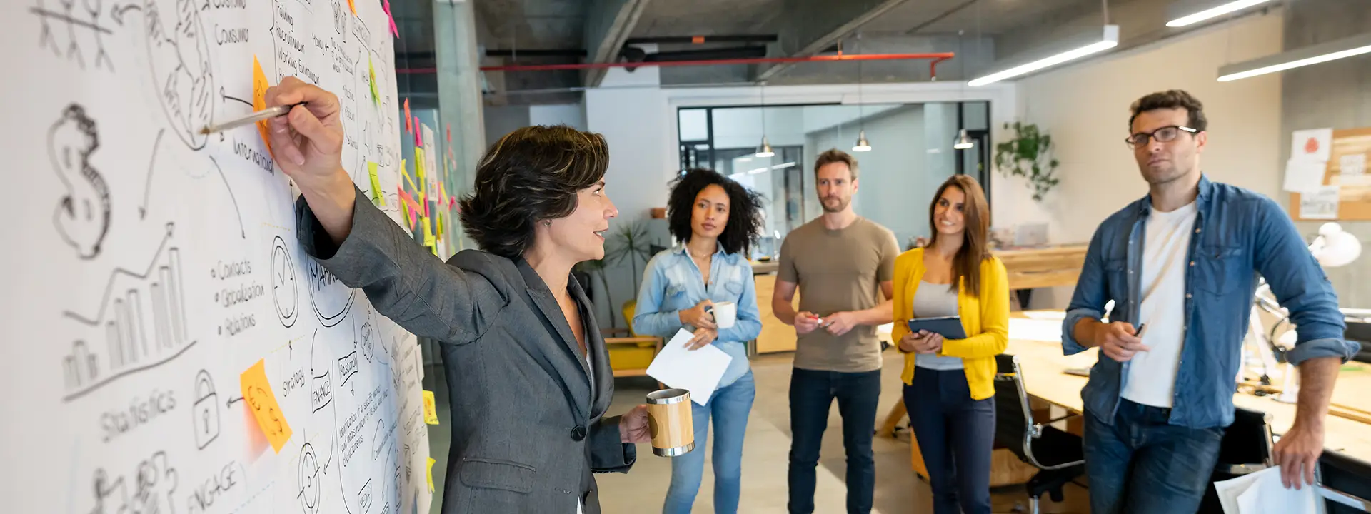 Latin American woman making a business presentation in a meeting at a creative office and pointing to her team her business plan