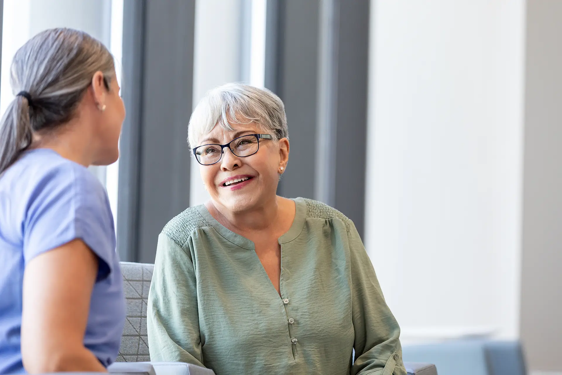 Senior adult woman smiles while talking to her doctor.